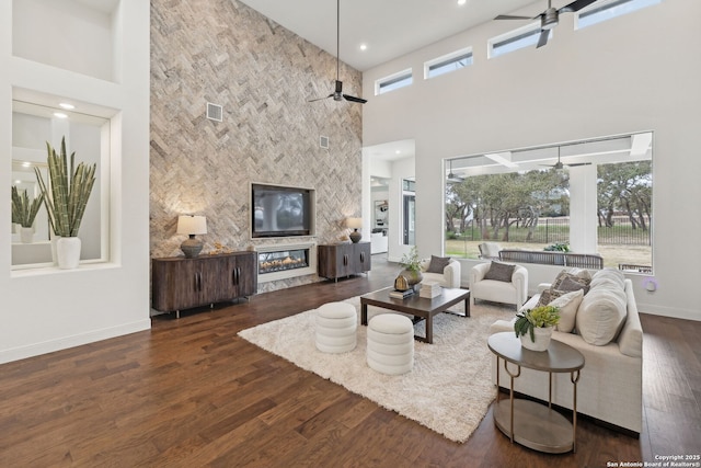 living room with a high ceiling, a tiled fireplace, and a wealth of natural light