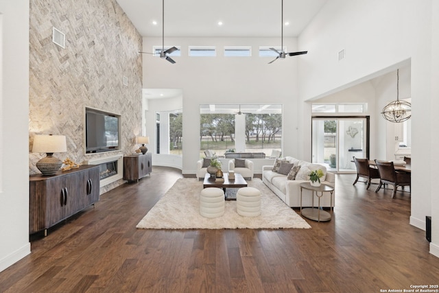 living room featuring ceiling fan with notable chandelier, a high ceiling, and a healthy amount of sunlight