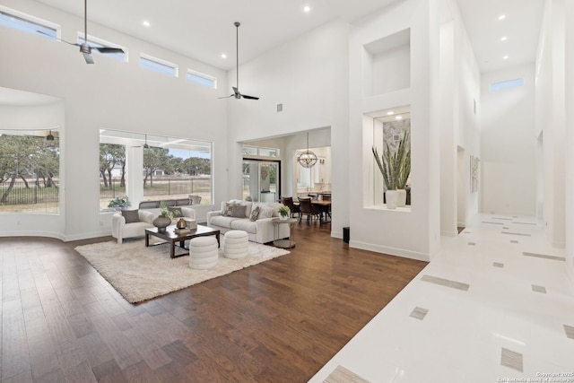 living room featuring ceiling fan with notable chandelier, a high ceiling, and dark hardwood / wood-style floors