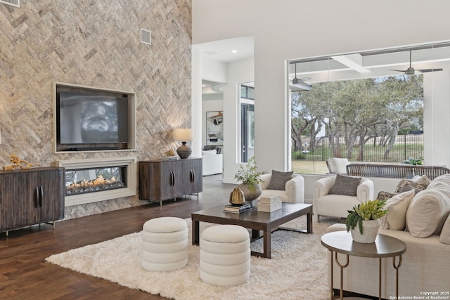 living room featuring a multi sided fireplace, ceiling fan, a wealth of natural light, and dark hardwood / wood-style floors