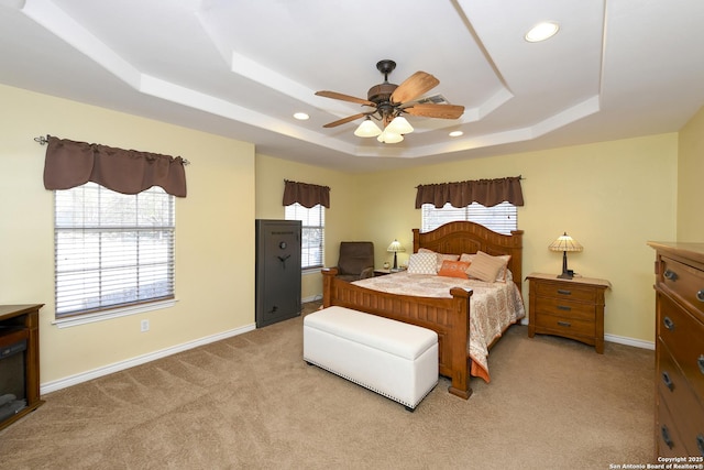 bedroom featuring ceiling fan, a raised ceiling, and light carpet