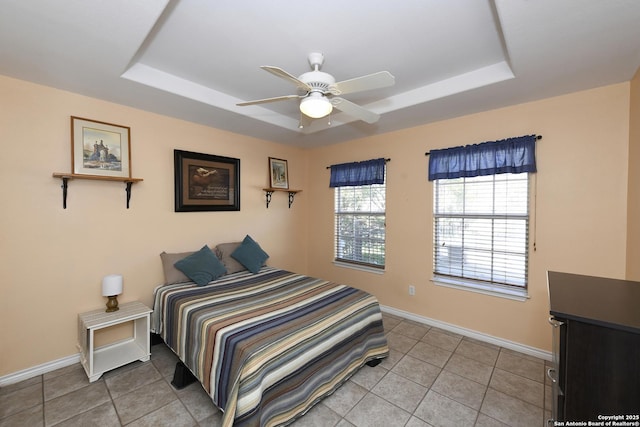 tiled bedroom with ceiling fan and a raised ceiling