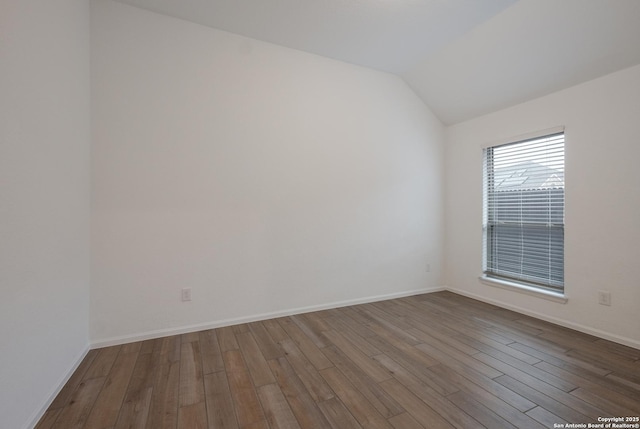 spare room with hardwood / wood-style flooring and lofted ceiling