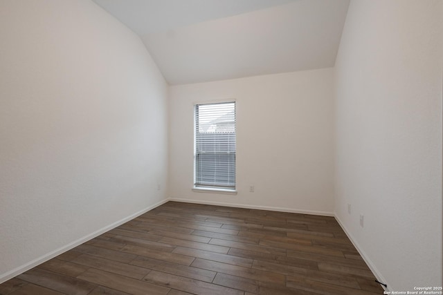 spare room featuring dark hardwood / wood-style flooring and vaulted ceiling