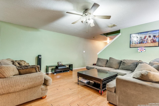 living room with a textured ceiling, ceiling fan, and light hardwood / wood-style flooring