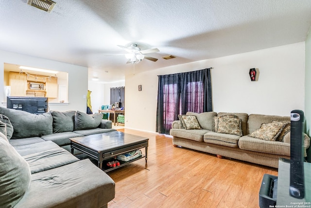 living room featuring a textured ceiling, ceiling fan, and hardwood / wood-style flooring