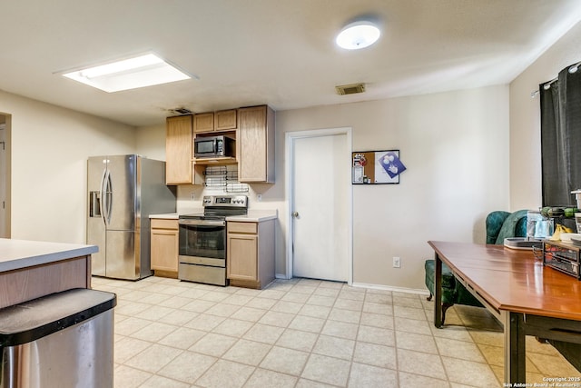 kitchen with light brown cabinetry and appliances with stainless steel finishes