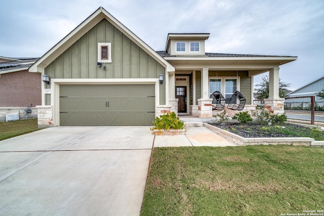 view of front of property featuring a front yard, covered porch, and a garage