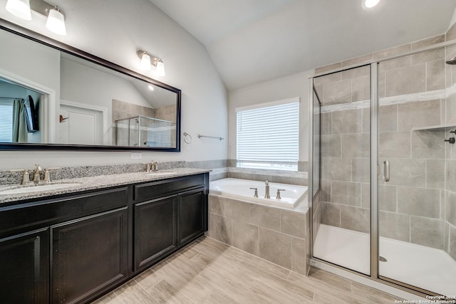 bathroom with independent shower and bath, vaulted ceiling, and vanity