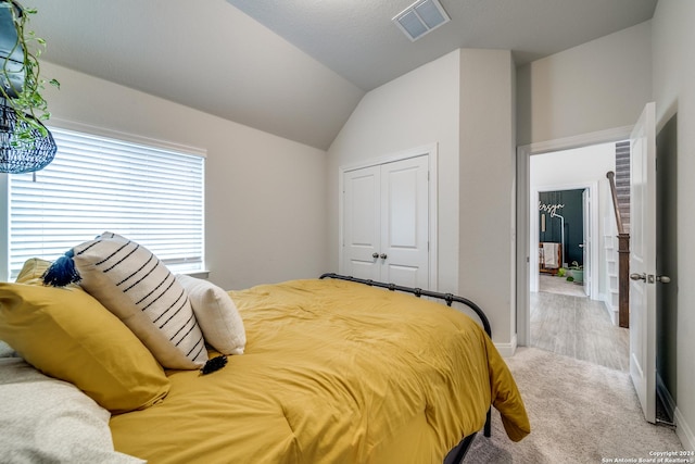 carpeted bedroom with lofted ceiling and a closet