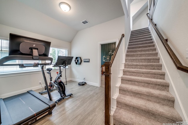 workout area with vaulted ceiling and light hardwood / wood-style floors