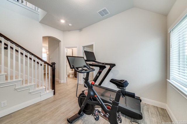 workout room featuring lofted ceiling and light hardwood / wood-style flooring