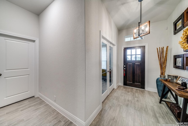 foyer entrance featuring a notable chandelier, french doors, and light hardwood / wood-style floors