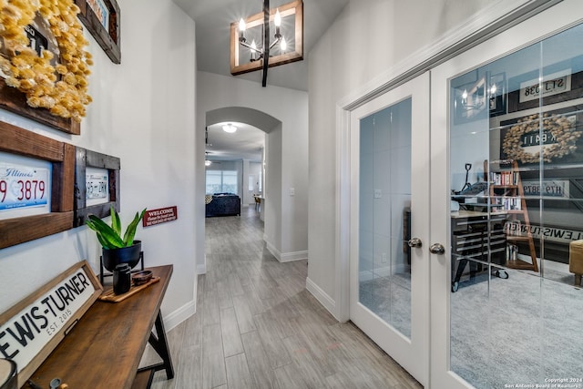 hallway with french doors and a notable chandelier