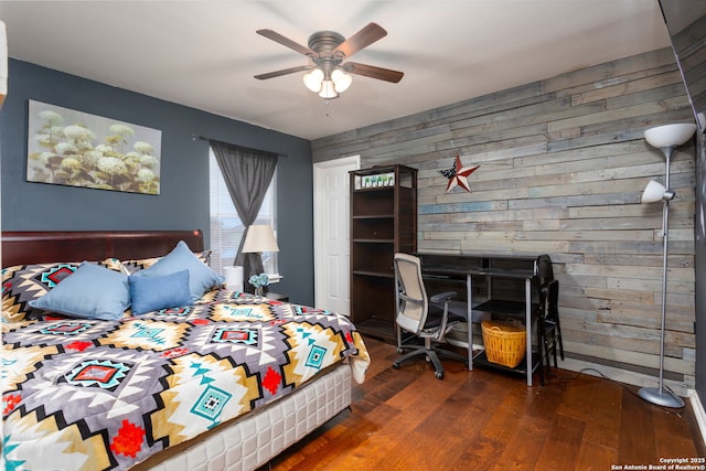 bedroom featuring wood walls, ceiling fan, and dark hardwood / wood-style floors