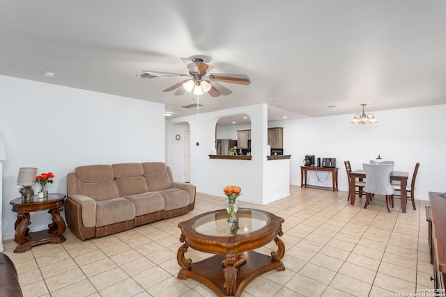 tiled living room with ceiling fan with notable chandelier