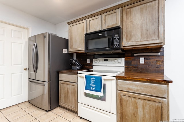 kitchen with electric range, light tile patterned flooring, light brown cabinets, and stainless steel refrigerator