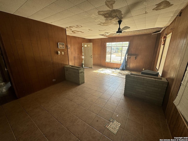 spare room featuring ceiling fan, wood walls, and tile patterned floors