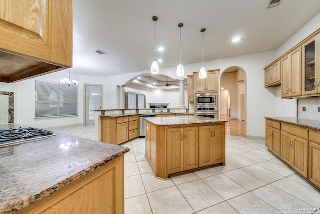 kitchen with stainless steel appliances, a center island, an inviting chandelier, light stone counters, and pendant lighting