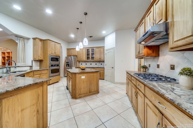 kitchen featuring stainless steel appliances, sink, decorative light fixtures, light stone countertops, and a kitchen island