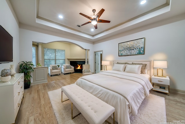 bedroom featuring ceiling fan, light hardwood / wood-style floors, and a raised ceiling