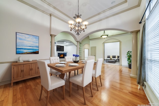 dining room with a raised ceiling, an inviting chandelier, light hardwood / wood-style floors, and crown molding