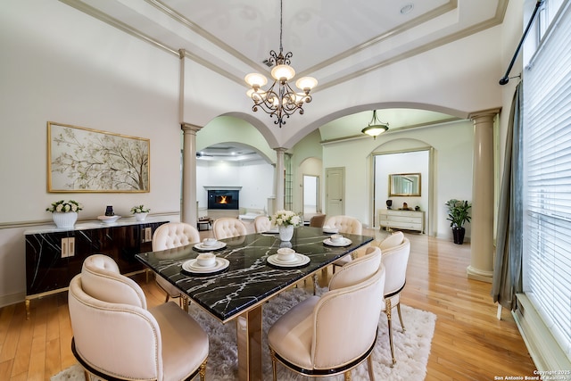 dining room featuring a chandelier, a tray ceiling, ornamental molding, and light hardwood / wood-style flooring