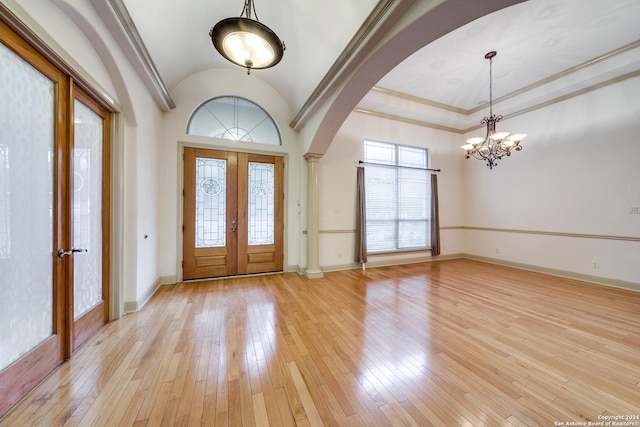 entrance foyer featuring vaulted ceiling, a notable chandelier, light wood-type flooring, and french doors