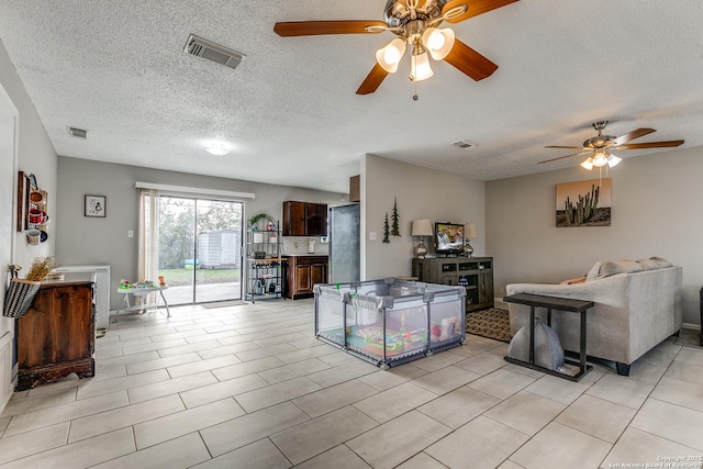 living room with a textured ceiling, ceiling fan, and light tile patterned floors