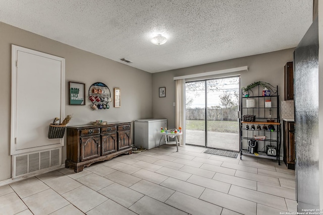 living area with a textured ceiling and light tile patterned floors