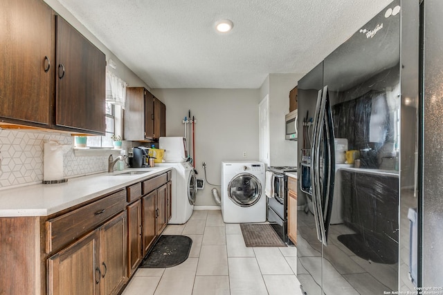 washroom with sink, light tile patterned floors, a textured ceiling, and separate washer and dryer