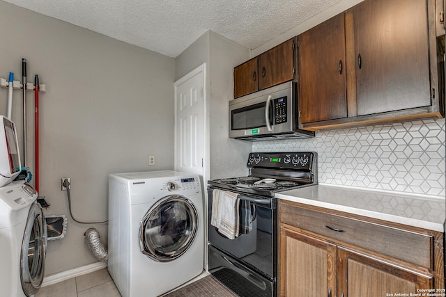 kitchen featuring black range with electric stovetop, washer / dryer, light tile patterned flooring, and a textured ceiling