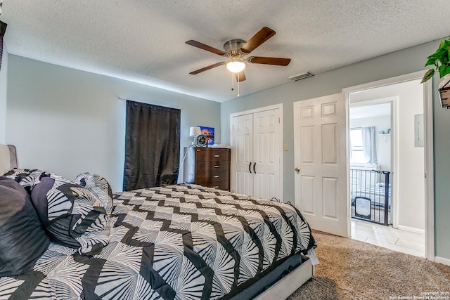 carpeted bedroom featuring a textured ceiling, ceiling fan, and a closet