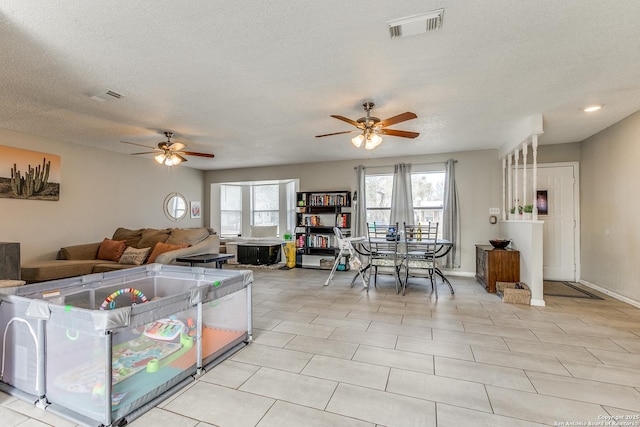 living room featuring a textured ceiling, ceiling fan, and light tile patterned floors