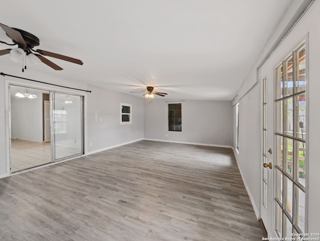 empty room featuring ceiling fan with notable chandelier and light hardwood / wood-style flooring