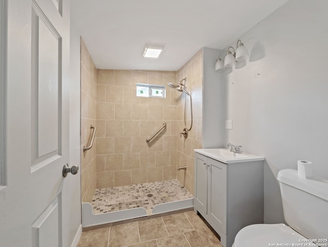 bathroom with toilet, a tile shower, and vanity