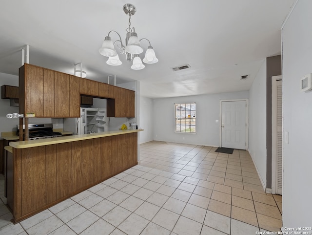 kitchen featuring an inviting chandelier, appliances with stainless steel finishes, kitchen peninsula, decorative light fixtures, and light tile patterned flooring