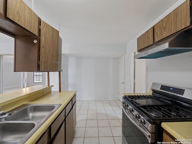 kitchen with range hood, light tile patterned floors, gas stove, and sink