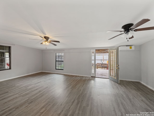 empty room with hardwood / wood-style floors, ceiling fan, french doors, and a wall mounted air conditioner