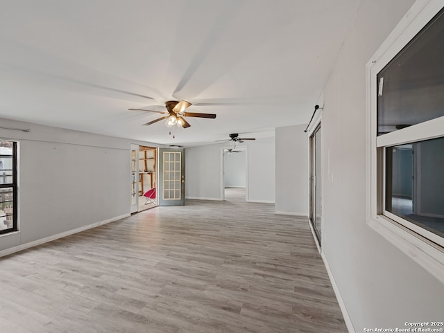 unfurnished room featuring ceiling fan, a barn door, and light hardwood / wood-style flooring