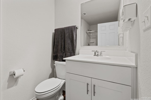 bathroom with walk in shower, vanity, and toilet