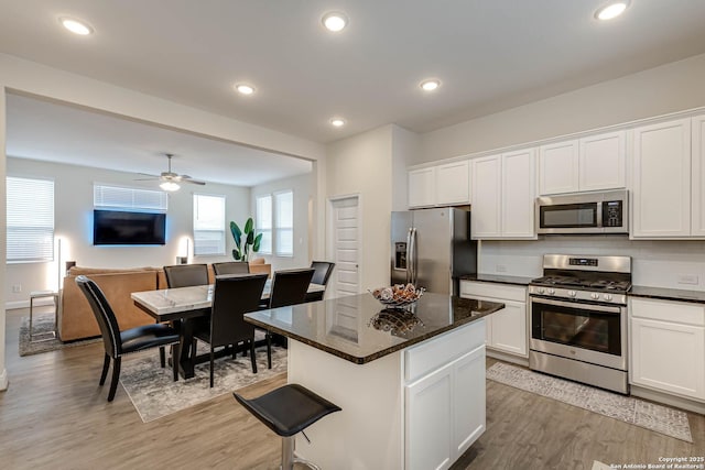 kitchen featuring white cabinets, ceiling fan, light hardwood / wood-style flooring, a kitchen island, and appliances with stainless steel finishes