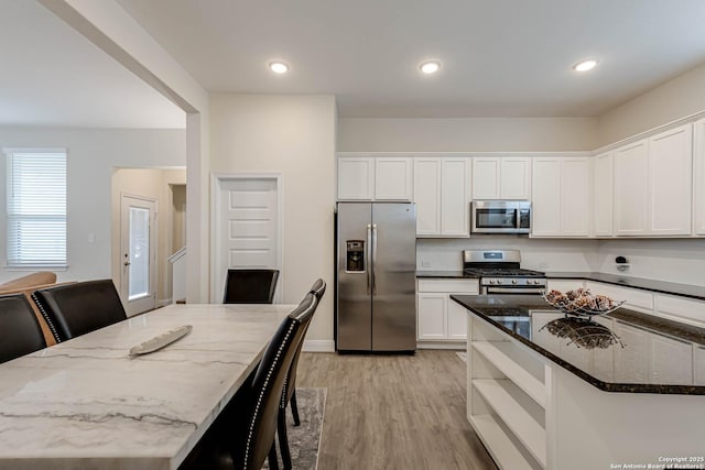 kitchen featuring stainless steel appliances, a center island, white cabinetry, and dark stone counters