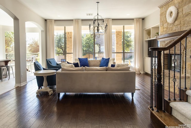 living room featuring a notable chandelier, dark hardwood / wood-style floors, plenty of natural light, and built in shelves