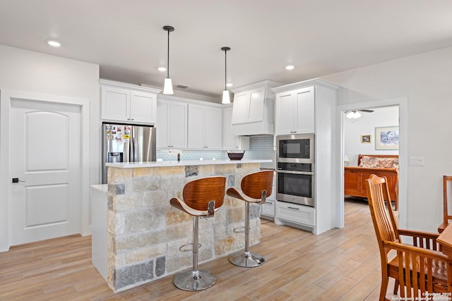 kitchen featuring appliances with stainless steel finishes, a center island, white cabinets, and tasteful backsplash