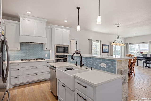 kitchen with stainless steel appliances, a kitchen island with sink, and pendant lighting