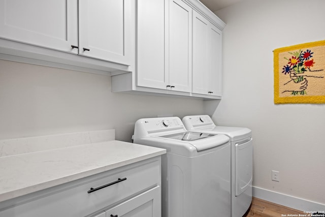 laundry area with separate washer and dryer, light hardwood / wood-style flooring, and cabinets