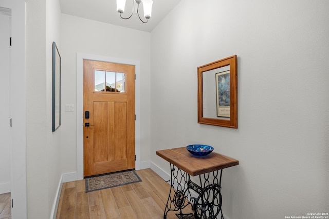 foyer entrance with light hardwood / wood-style flooring and a chandelier