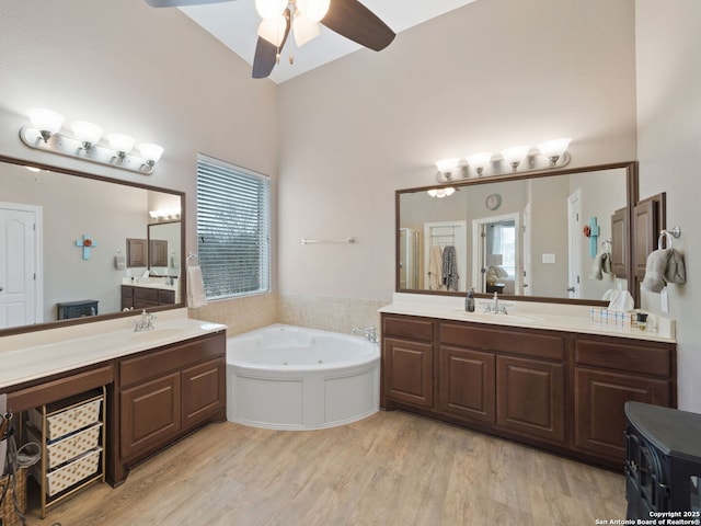 bathroom featuring wood-type flooring, vanity, ceiling fan, and a bathing tub