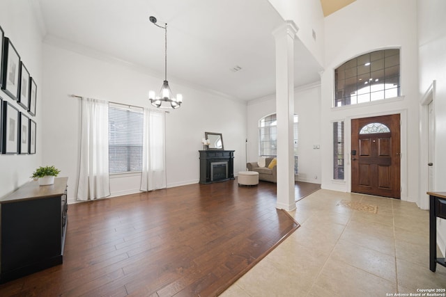 foyer with hardwood / wood-style floors, decorative columns, a healthy amount of sunlight, and a notable chandelier